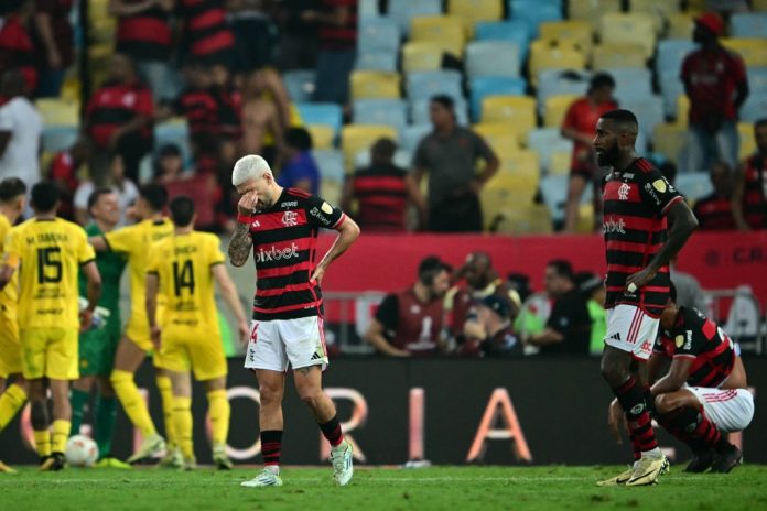 Flamengo's Uruguayan midfielder Giorgian de Arrascaeta (C) and midfielder Gerson react after losing the Copa Libertadores quarter-final first leg football match between Brazil's Flamengo and Uruguay's Peñarol at the Maracana stadium in Rio de Janeiro, Brazil, on September 19, 2024. (Photo by Mauro PIMENTEL / AFP)