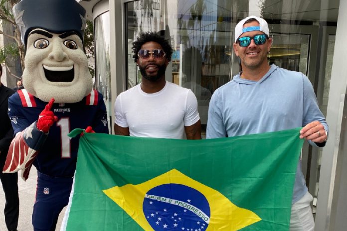 O mascote Pat Patriot, Malcolm Butler e Stephen Gostkowski posam com a bandeira do Brasil: estrelas de festa em bar de São Paulo