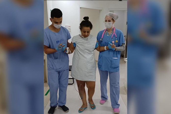 Imagem mostra mulher em hospital sendo amparada por dois profissionais de saúde - Metrópoles