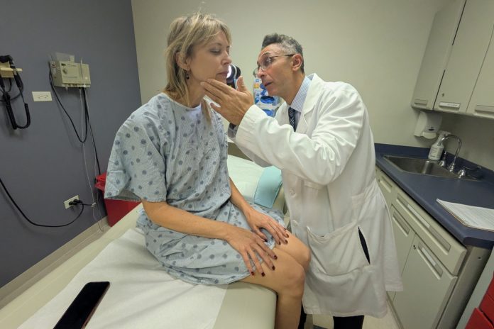 Pedram Gerami examina a pele da paciente e sobrevivente de melanoma Heidi Tarr.